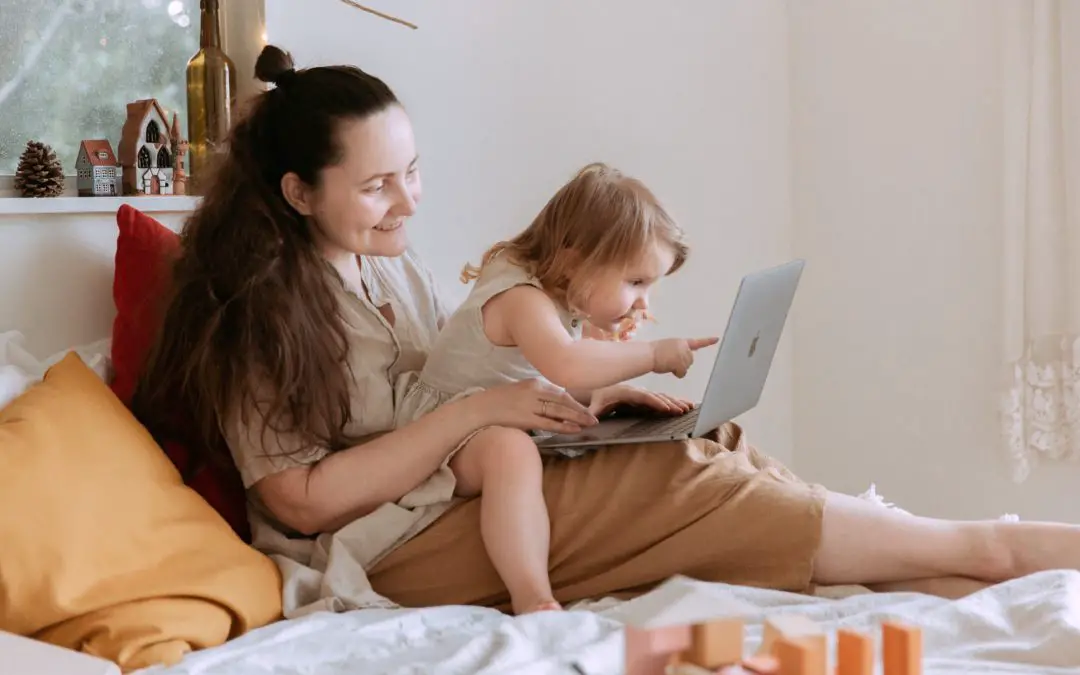 mother and child sitting on bed looking at computer for blog content