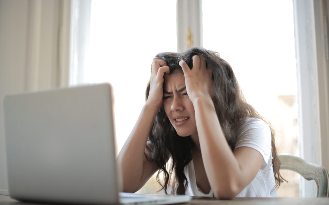 woman holding head frustrated at computer making blogging mistakes
